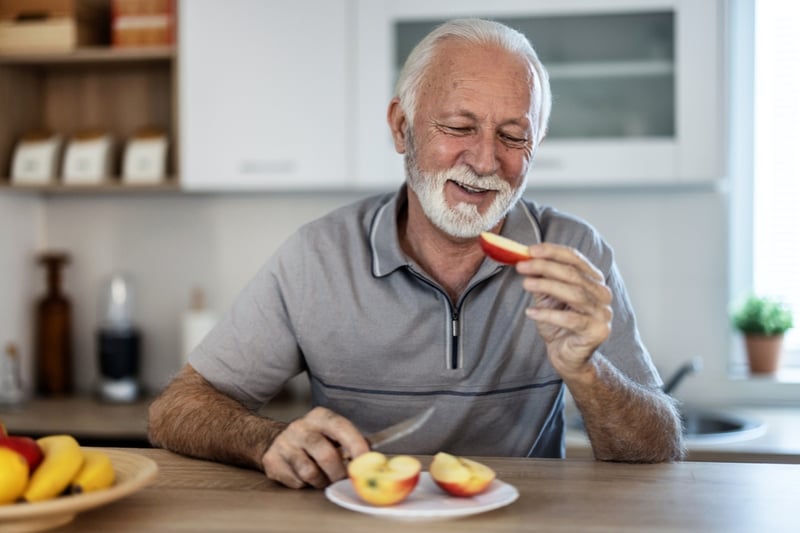 Mann isst Apfel gegen Naehrstoffmangel bei Senioren