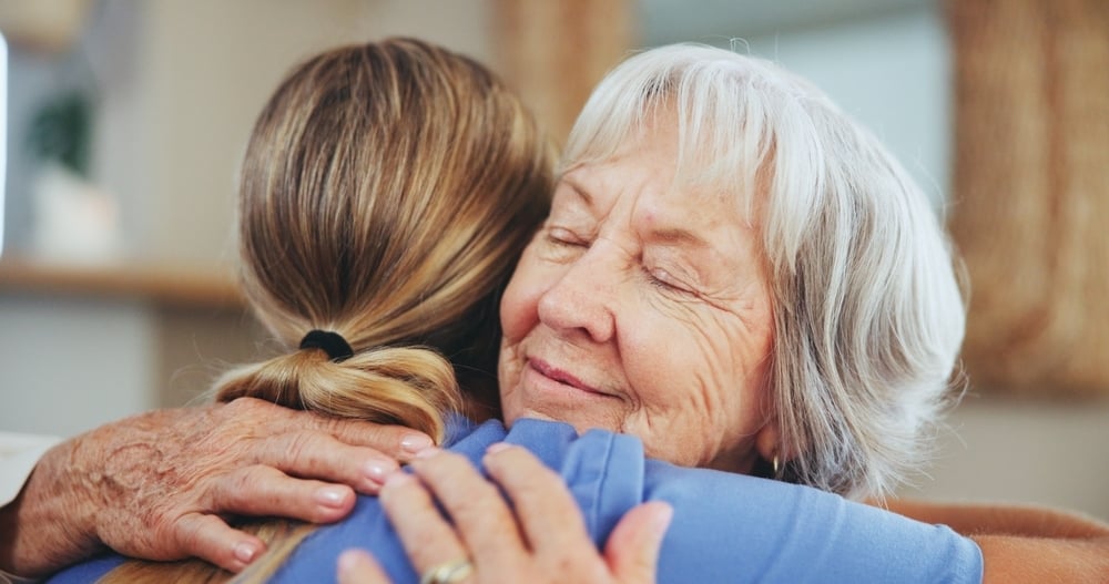 Eine Krankenschwester umarmt eine Seniorin